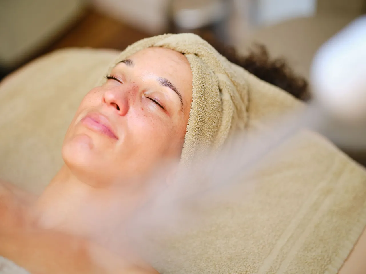 A relaxed client with closed eyes under soft facial steam
