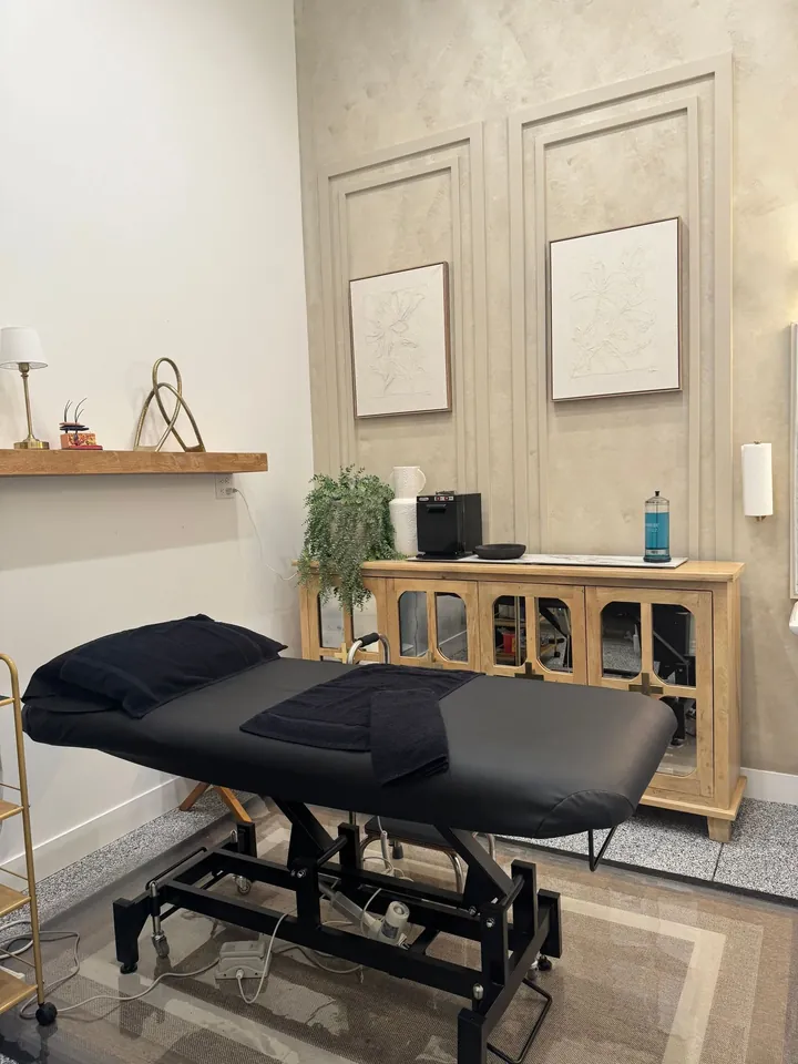 A private treatment room with a black bed and soft neutral walls